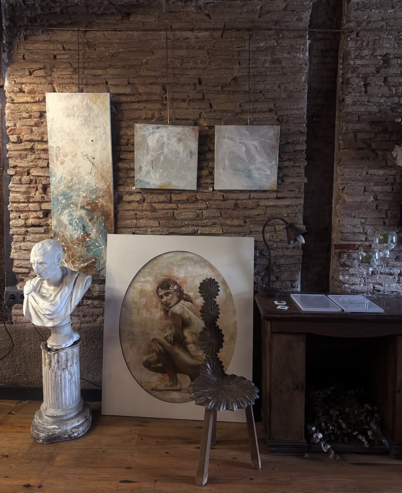 Busto romano de escayola sobre una columna, junto a un óleo de figura en un óvalo